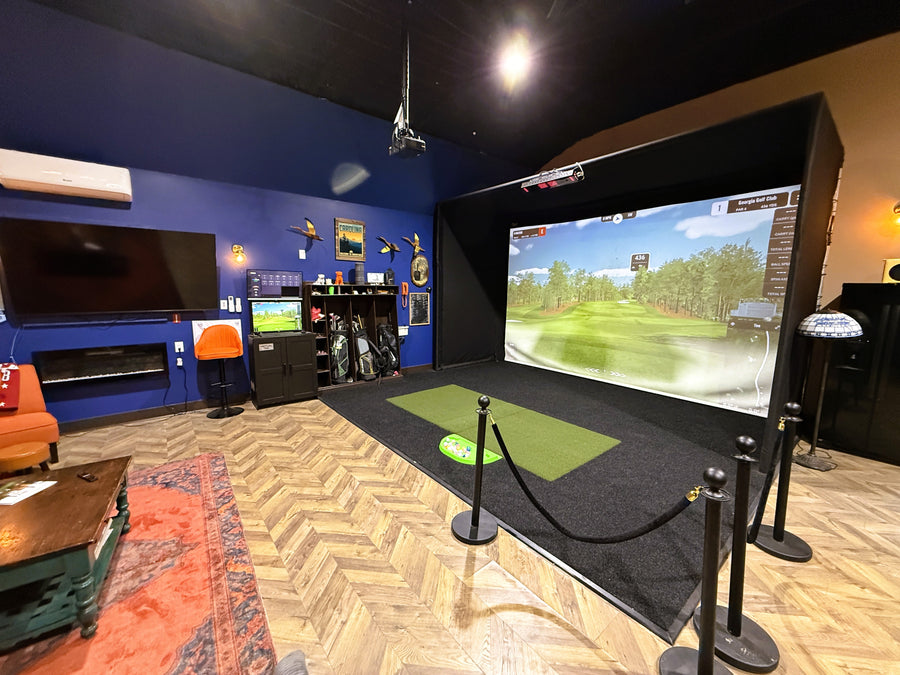 Indoor golf simulator setup in a room with a large screen displaying a golf course.