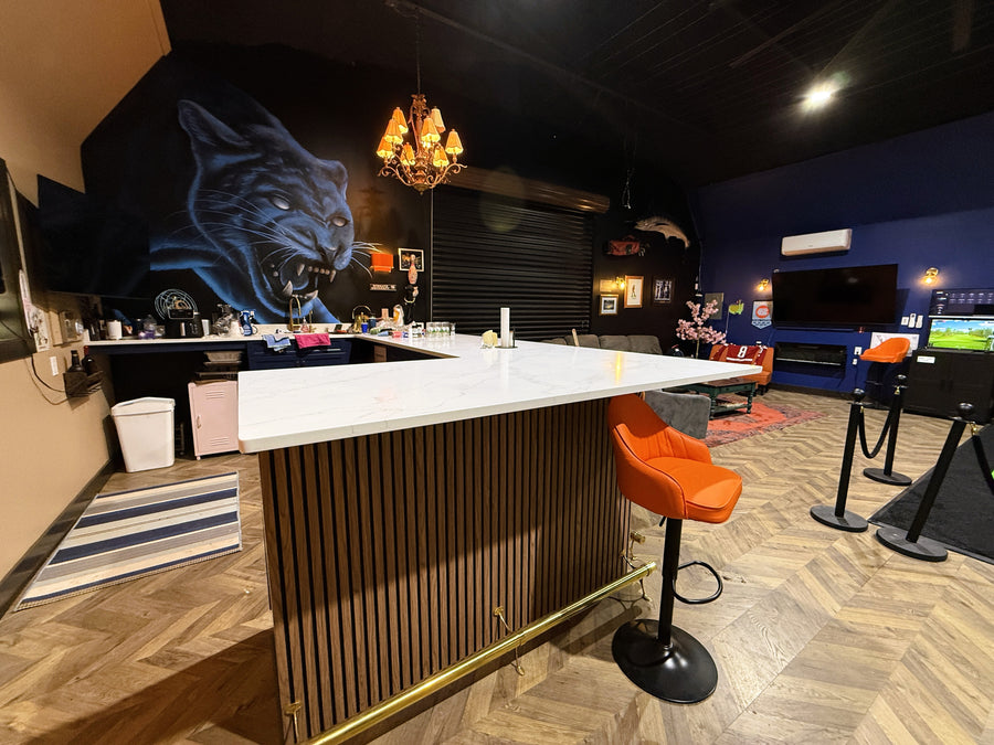 Modern bar area with a large screen displaying a blue panther, surrounded by golf simulator equipment.