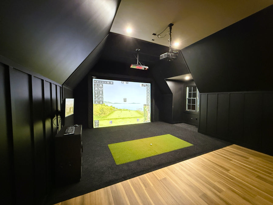 Indoor golf simulator room with a screen displaying a golf course.