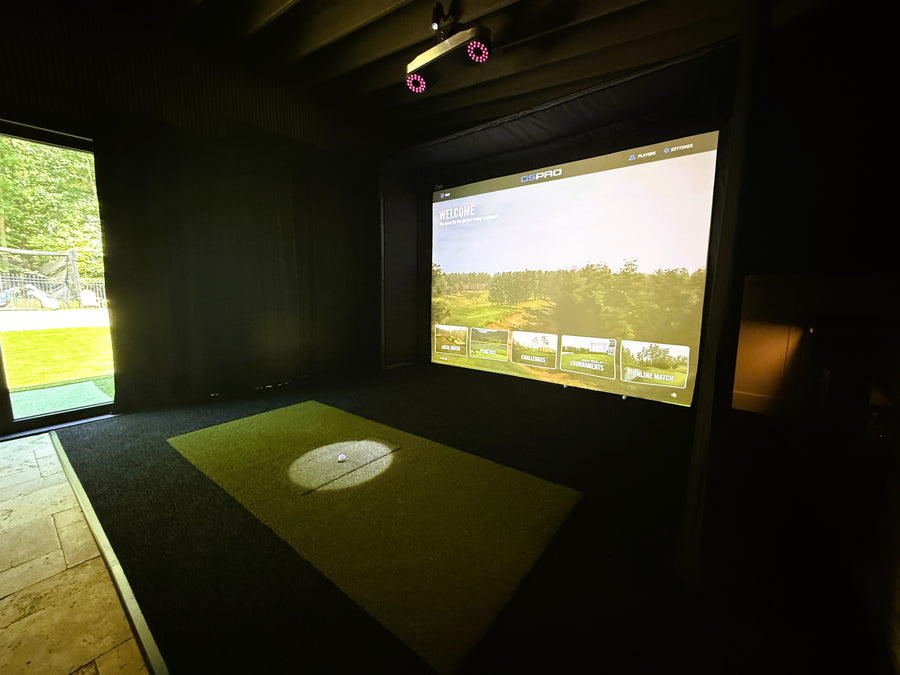 Indoor golf simulator setup with screen displaying a golf course.