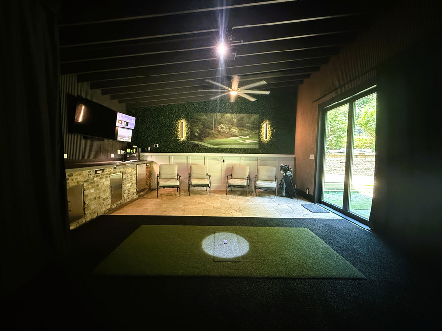 Indoor golf simulator setup in a home with a screen displaying a golf course.