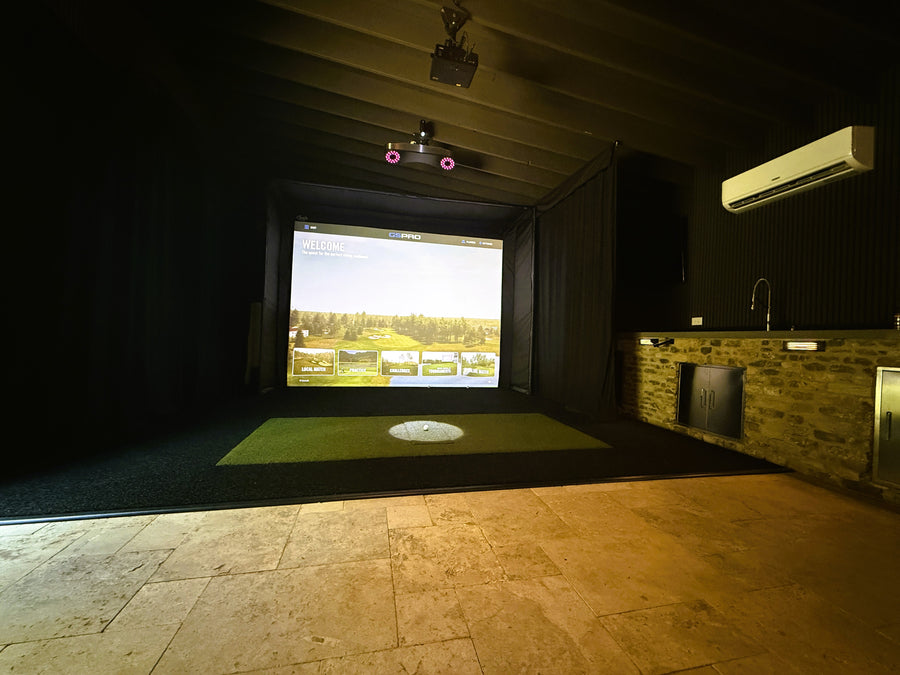 Indoor golf simulator setup with screen displaying a golf course.