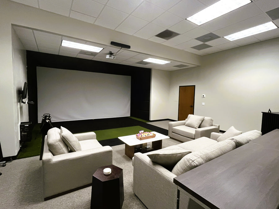 Golf Simulator room with white sofas, a coffee table, and a movie screen.