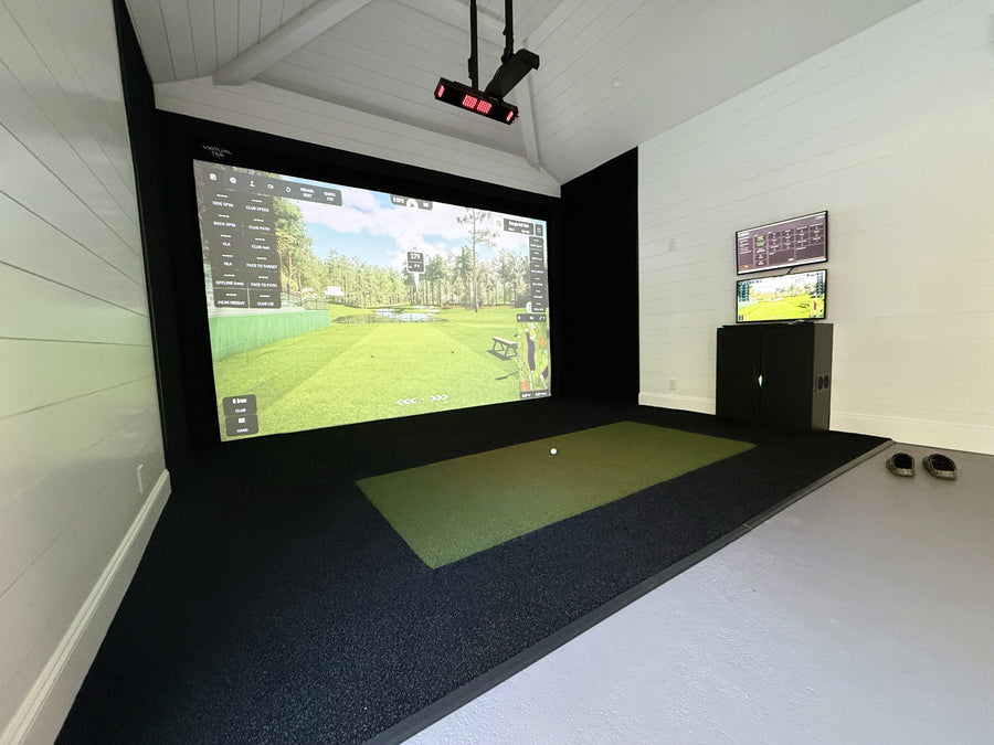 Indoor golf simulator setup with two screens displaying a golf course.
