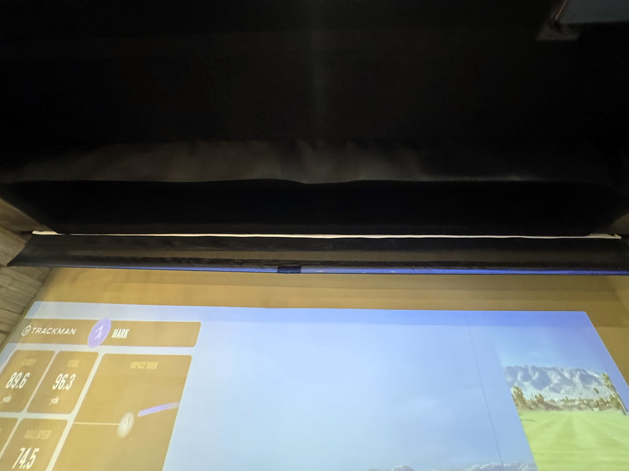 Retractable golf simulator setup with screen displaying a golf simulation game