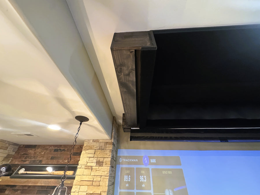 Retractable golf simulator with a stone wall and ceiling lights.