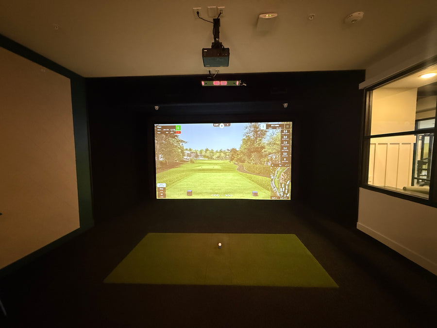 Apartment golf simulator with screen displaying golf course.