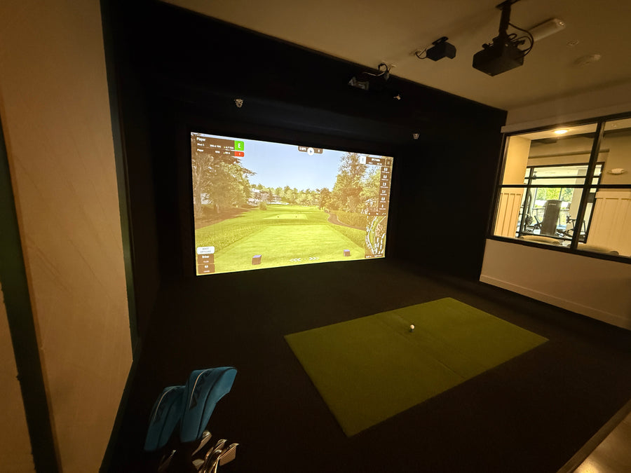 Apartment golf simulator with screen displaying golf course.
