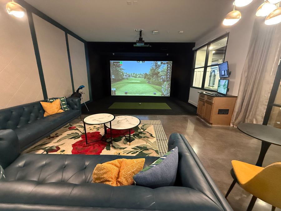 Apartment golf simulator with screen displaying golf course.