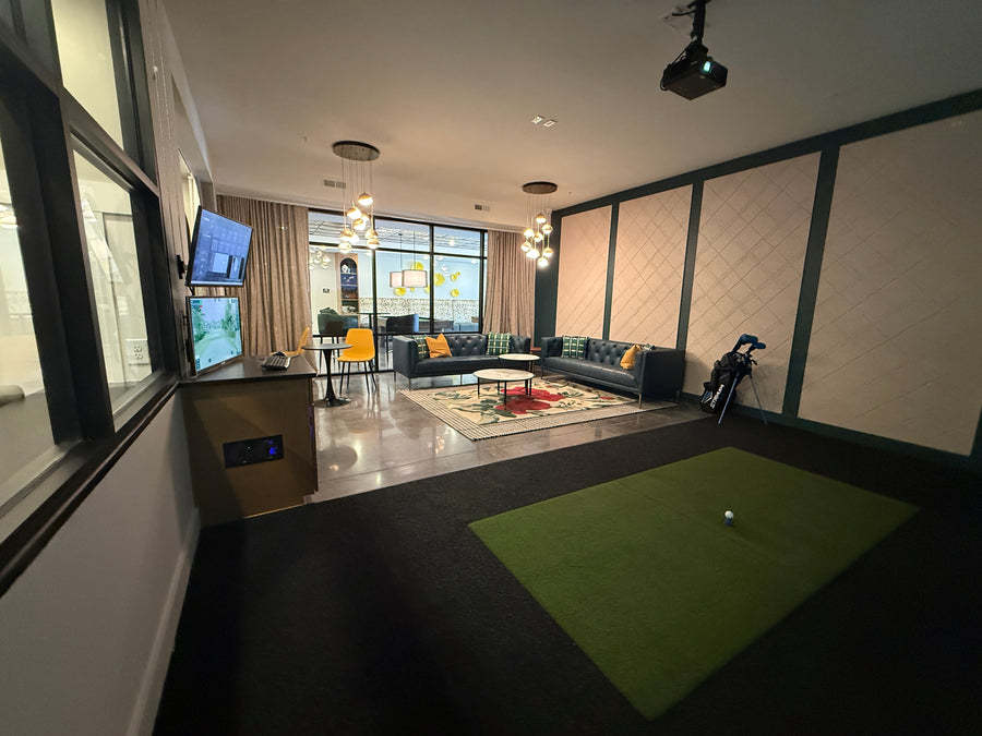 Lounge area behind golf simulator with seating.