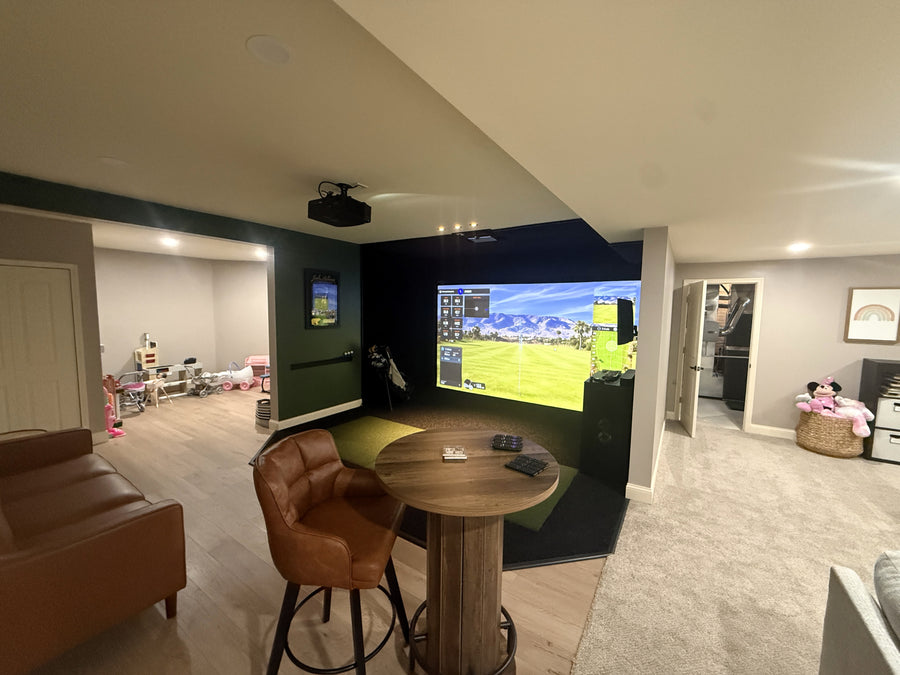 Living room with a golf simulator screen displaying a golf round, surrounded by furniture and decor.