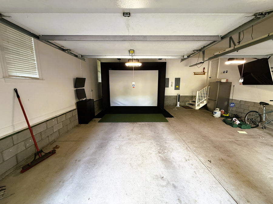 Garage converted into a golf simulator with a projector and screen.
