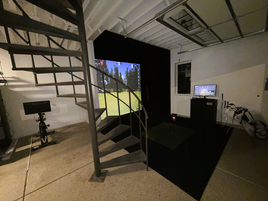 Spiral staircase leading down to a garage golf simulator setup.