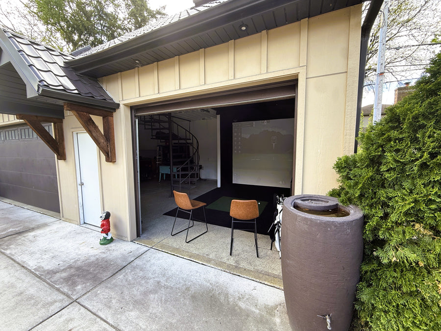 Outside view into a garage golf simulator setup.