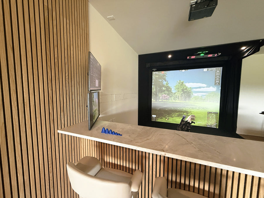 Modern golf simulator with a large screen displaying a game, surrounded by wooden paneling.