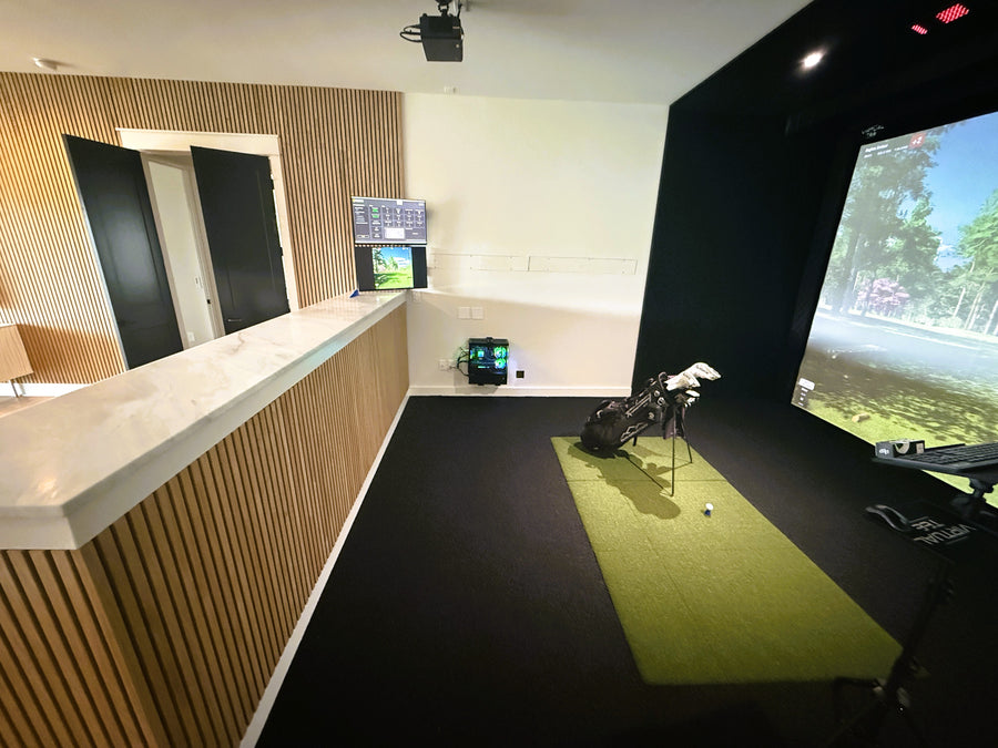 Golf simulator room with a screen displaying a golf course and a golf club on a green mat.