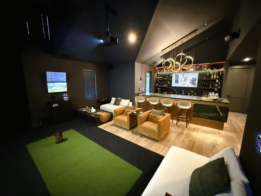 Indoor golf simulator and gaming room with multiple screens and comfortable seating.