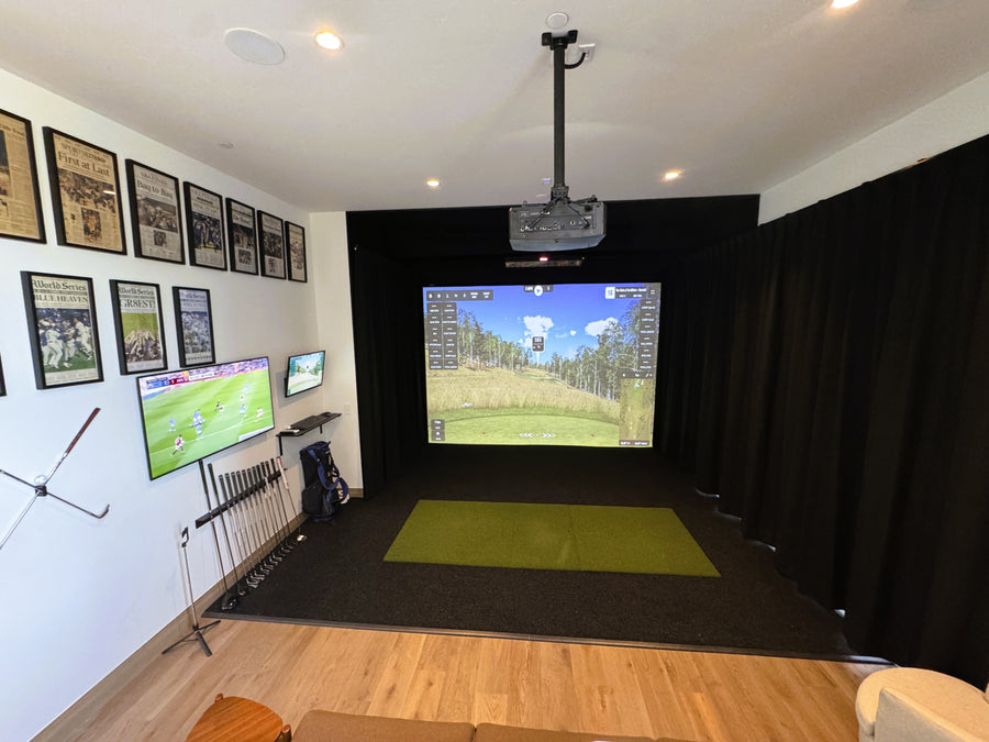 Golf simulator setup in a room with multiple screens and a projection system.