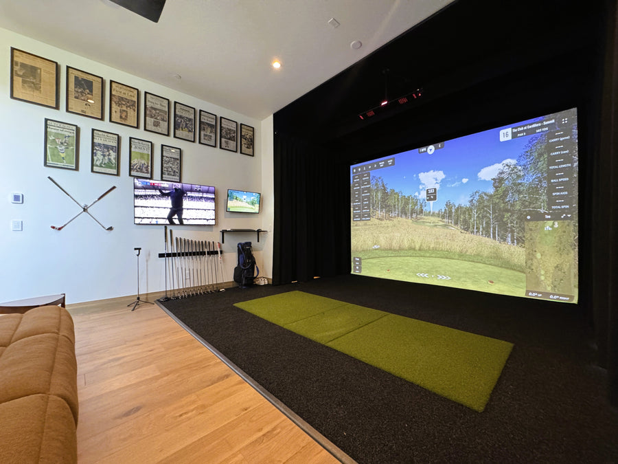 Indoor golf simulator setup with large screen and surrounding decor