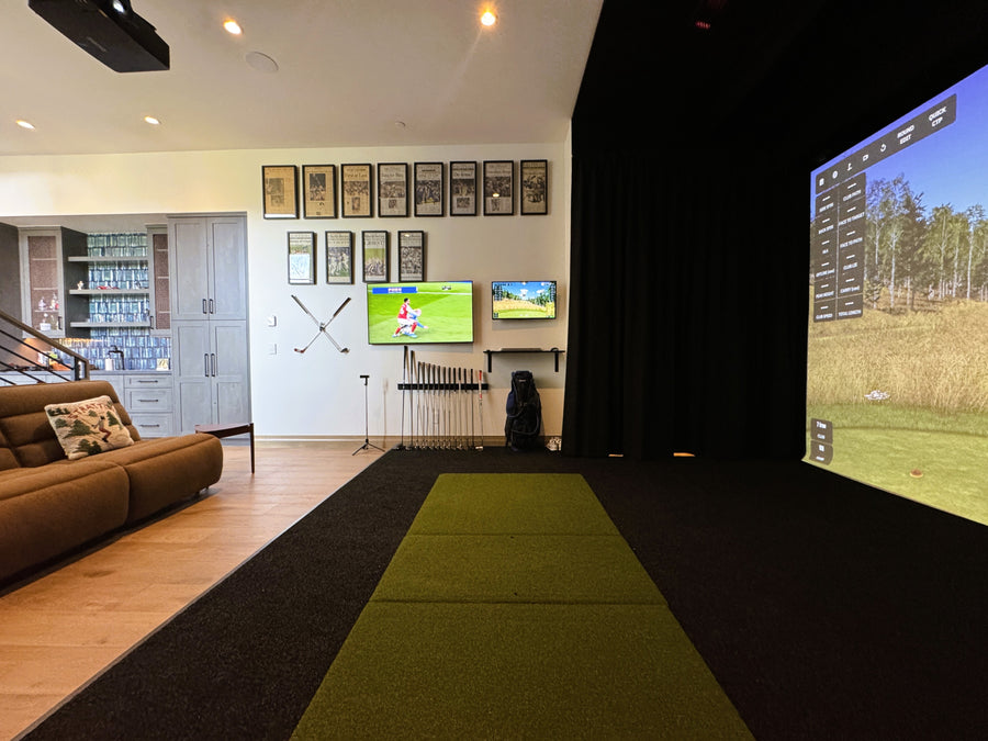 Indoor golf simulator setup in a living room with multiple screens displaying golf graphics.