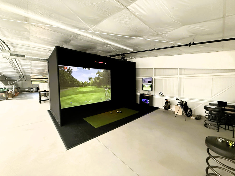 Indoor golf simulator setup in a room with a large screen displaying a golf course.