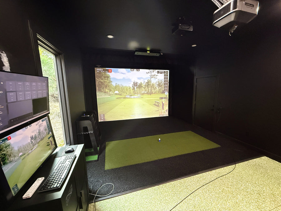 Indoor golf simulator setup with multiple screens and a projection screen.