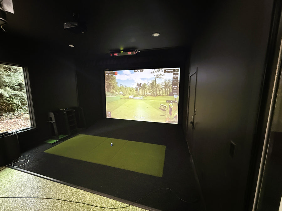 Indoor golf simulator setup with screen displaying a golf course.