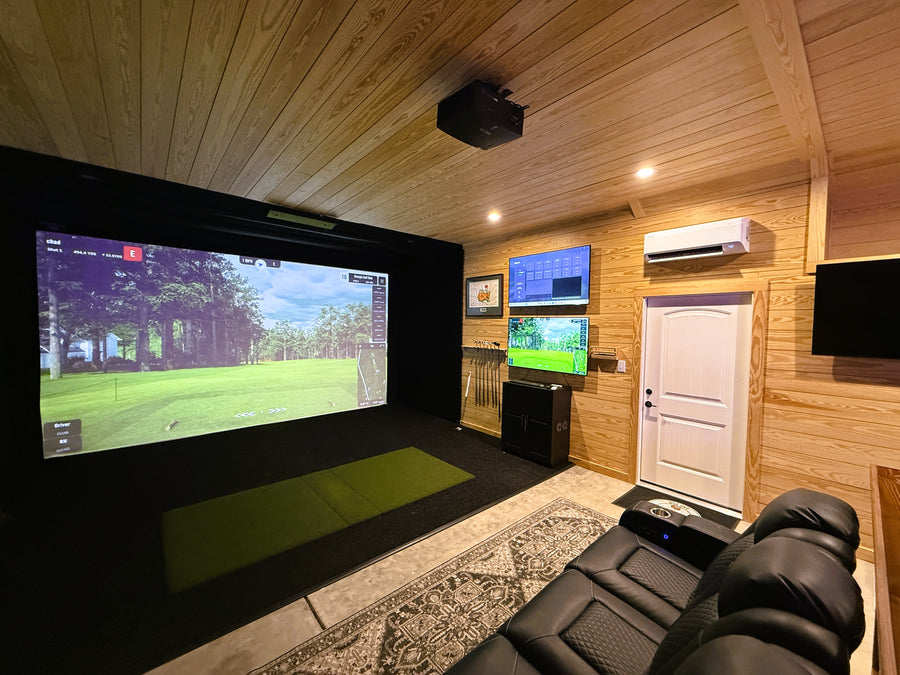 Indoor golf simulator room with multiple screens displaying video games, surrounded by wooden walls.