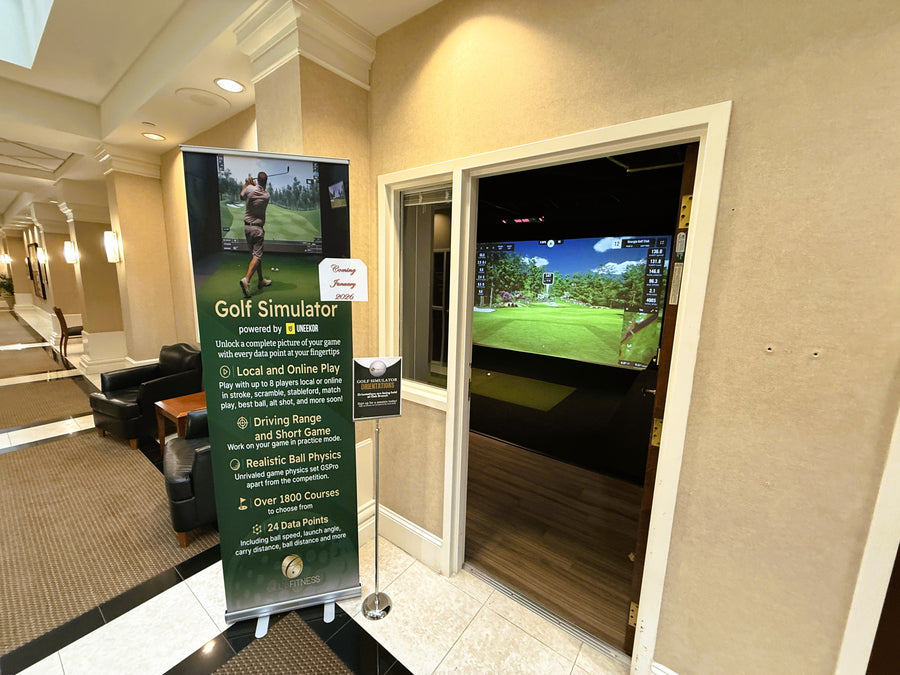 Golf simulator setup in a room with a large screen displaying a golf course.