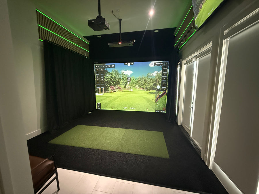 Indoor golf simulator setup with screen displaying a golf course.