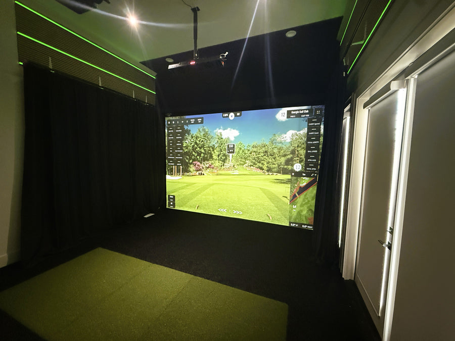 Indoor golf simulator setup with a screen displaying a golf course.
