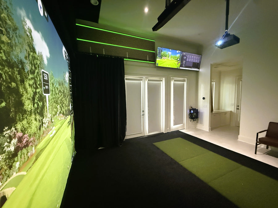 Indoor golf simulator setup with large screen and projection equipment.