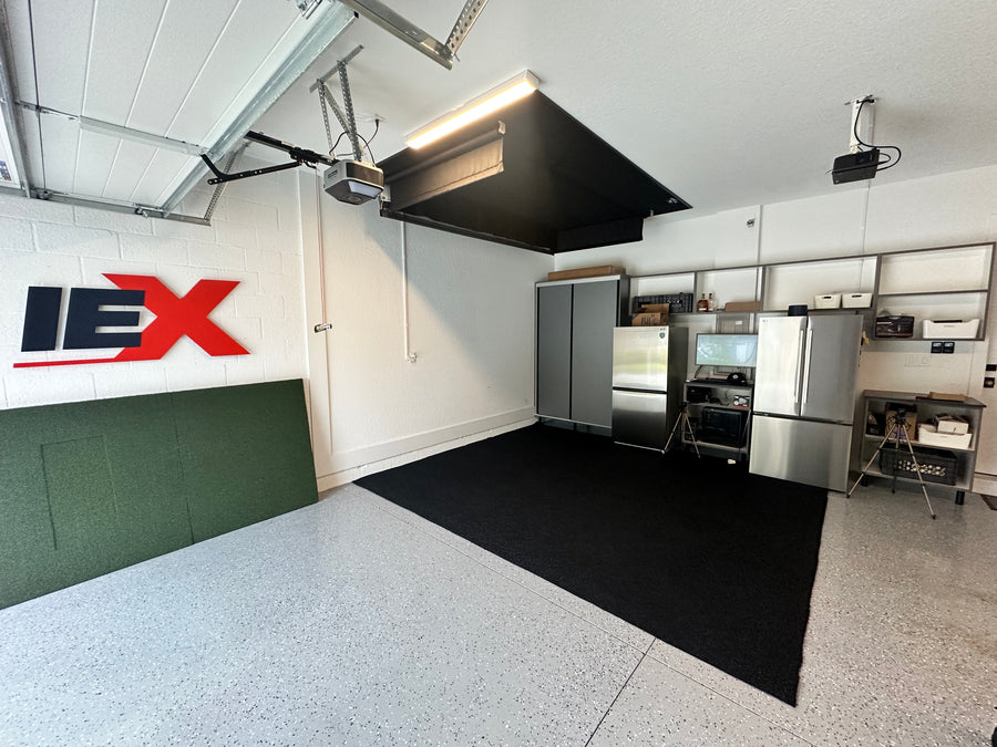 Modern garage with retractable golf simulator, featuring a black mat on the floor.