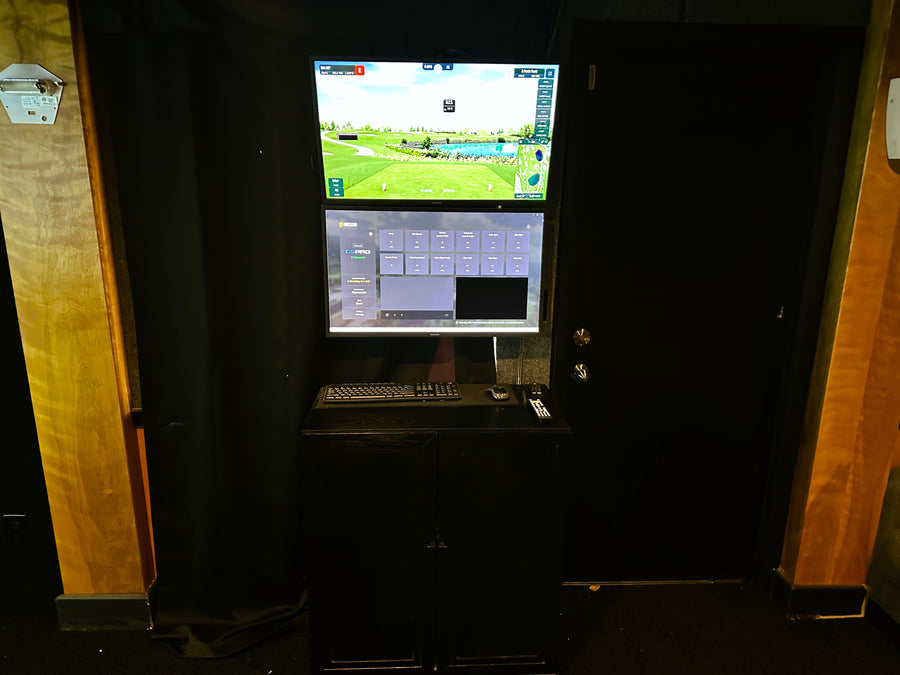 Golf simulator setup with screen displaying a golf course on a wooden panel background