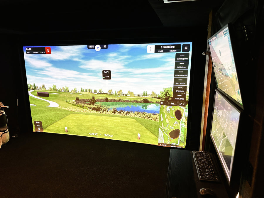 Golf simulator setup with two screens displaying a golf course.