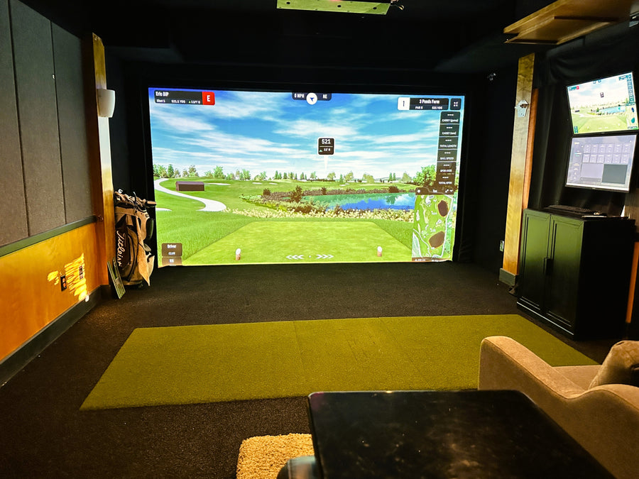 Indoor golf simulator setup with large screen displaying a virtual golf course.
