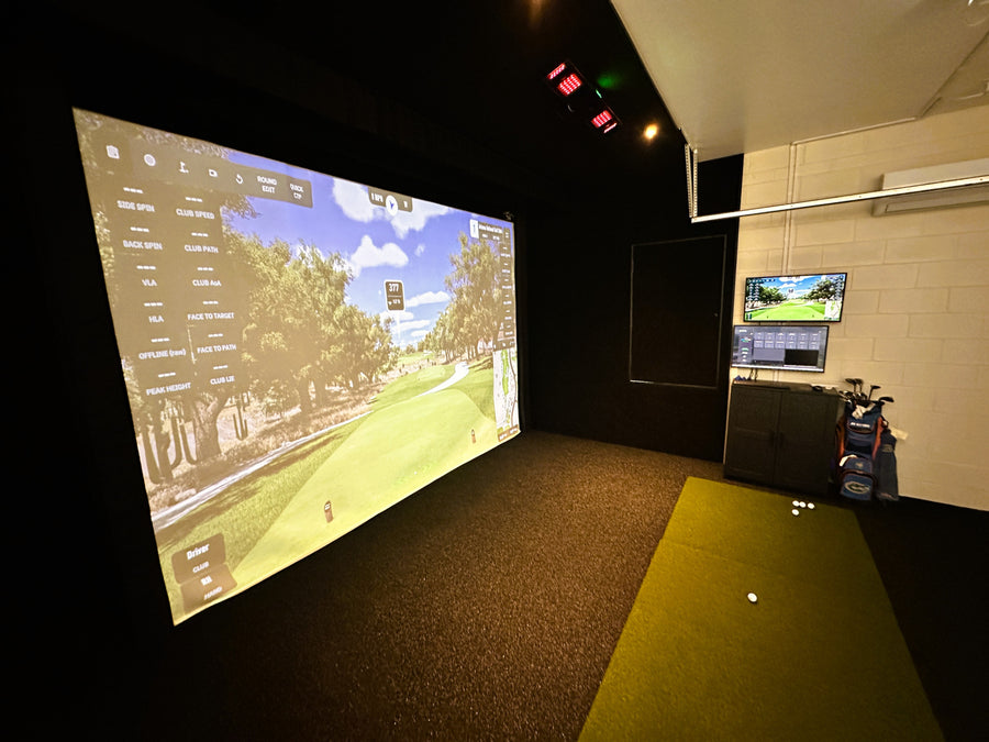 Indoor golf simulator setup with large screen displaying a golf course.