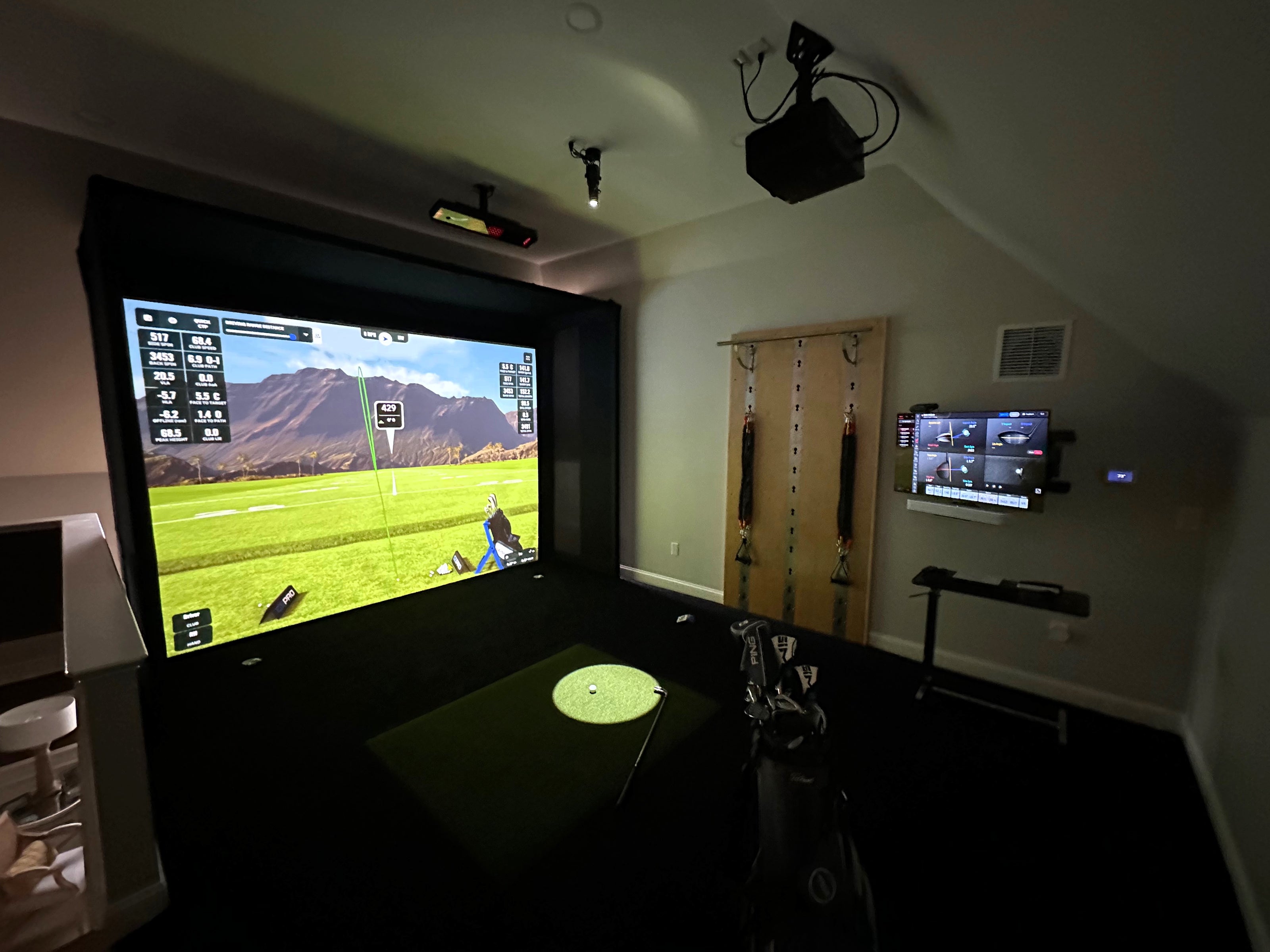 A home golf simulator in a loft space featuring a custom cage system.