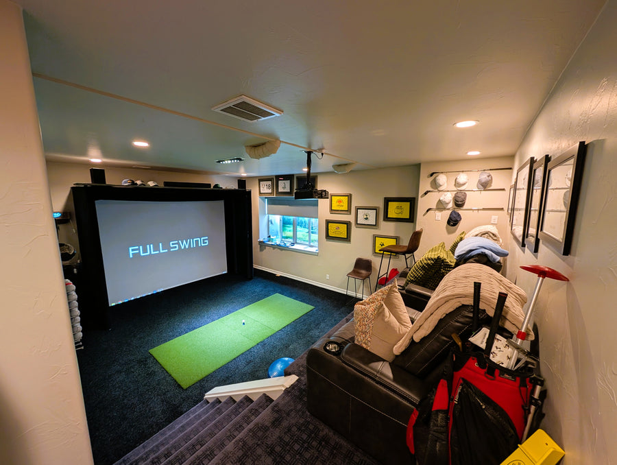 Indoor golf simulator setup in a room with a screen displaying 'FULL SWING'.