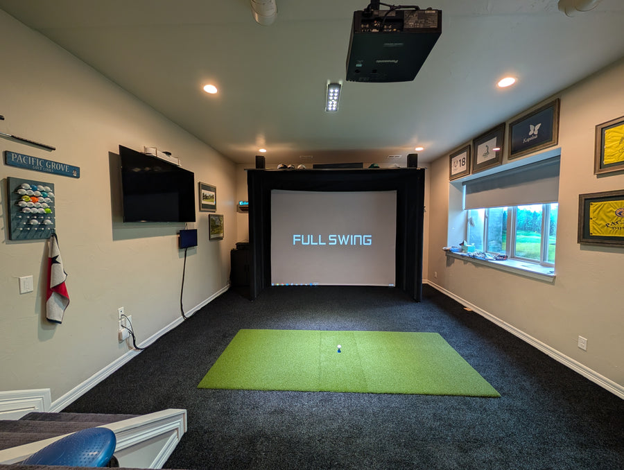 Indoor golf simulator room with green mat and screen displaying 'Full Swing'.