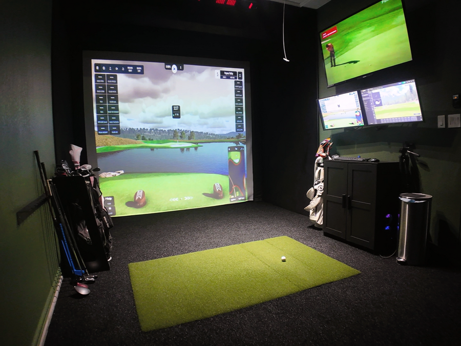 Golf simulator setup with multiple screens displaying golf games in a room.