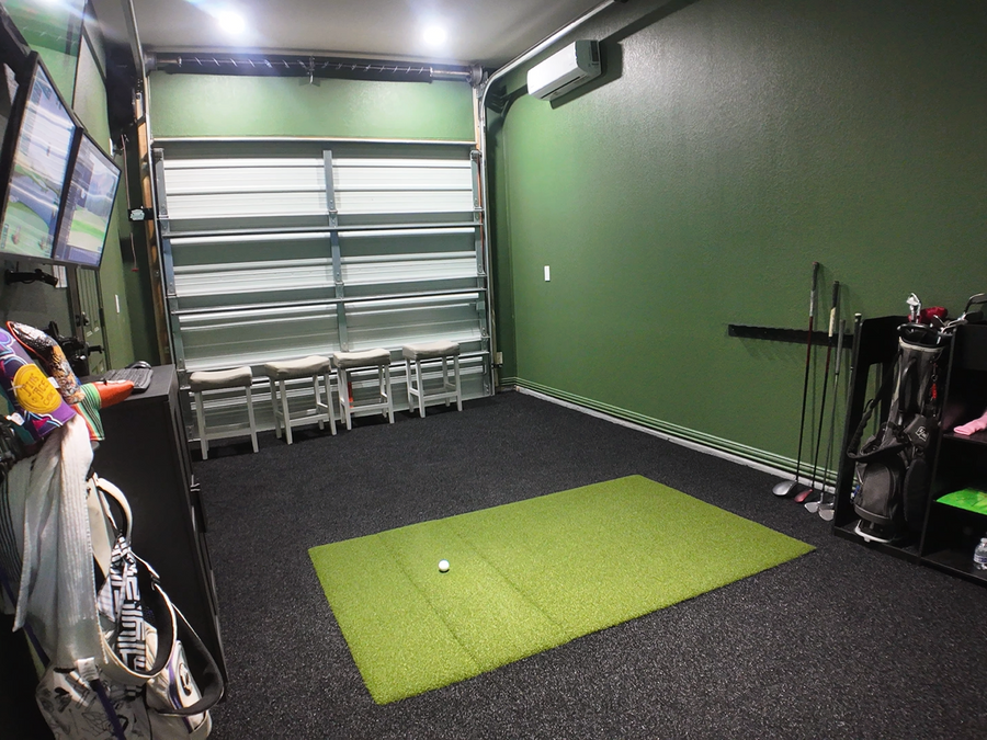 Indoor golf practice area with green mat, golf clubs, and equipment.