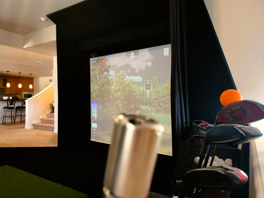 Indoor golf simulator setup with a large screen displaying a video game, surrounded by home decor.