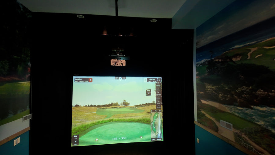 Golf simulator setup with screen displaying a golf course on a wall with maps.