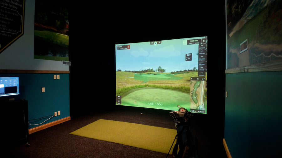 Golf simulator setup with screen displaying a golf course and camera equipment.