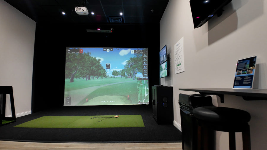 Golf simulator room with large screen displaying a golf course.