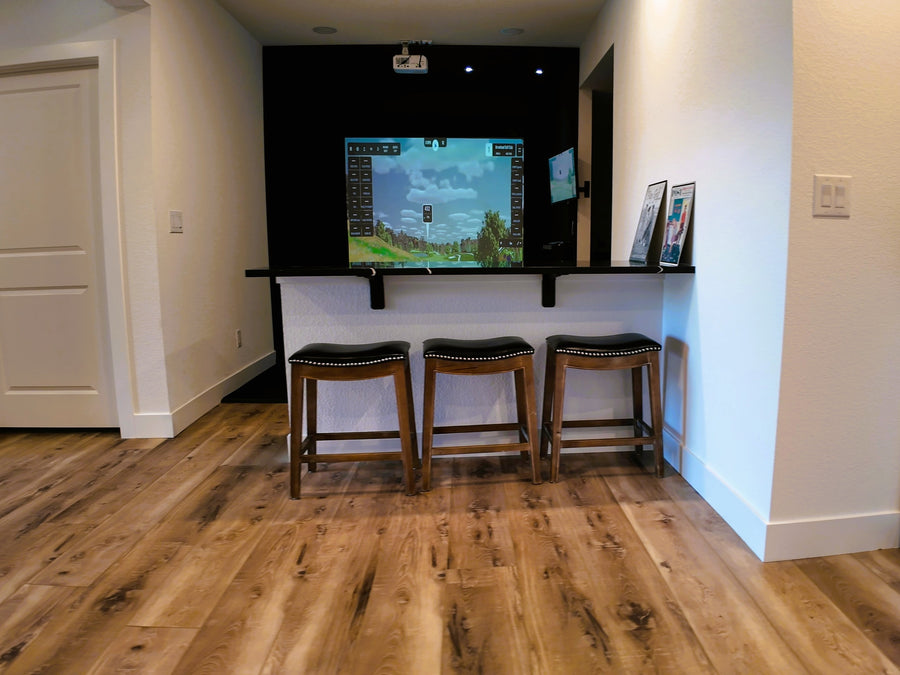 basement golf simulator featuring a bar top and seating
